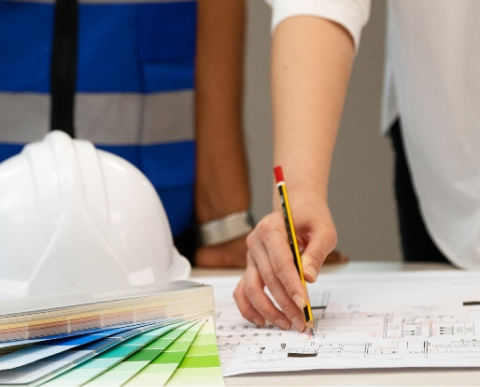 Close-up of a project manager reviewing plans with a pencil